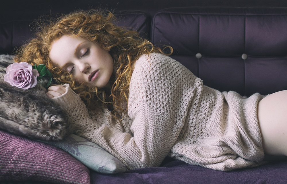 Image of redhaired model Ivory Flame sleeping with purple rose by photographer Rob Ellis